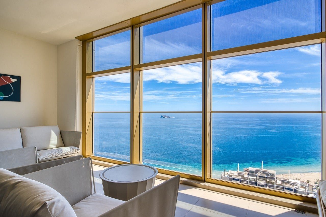 Sunlit living room with floor-to-ceiling windows and a sea view