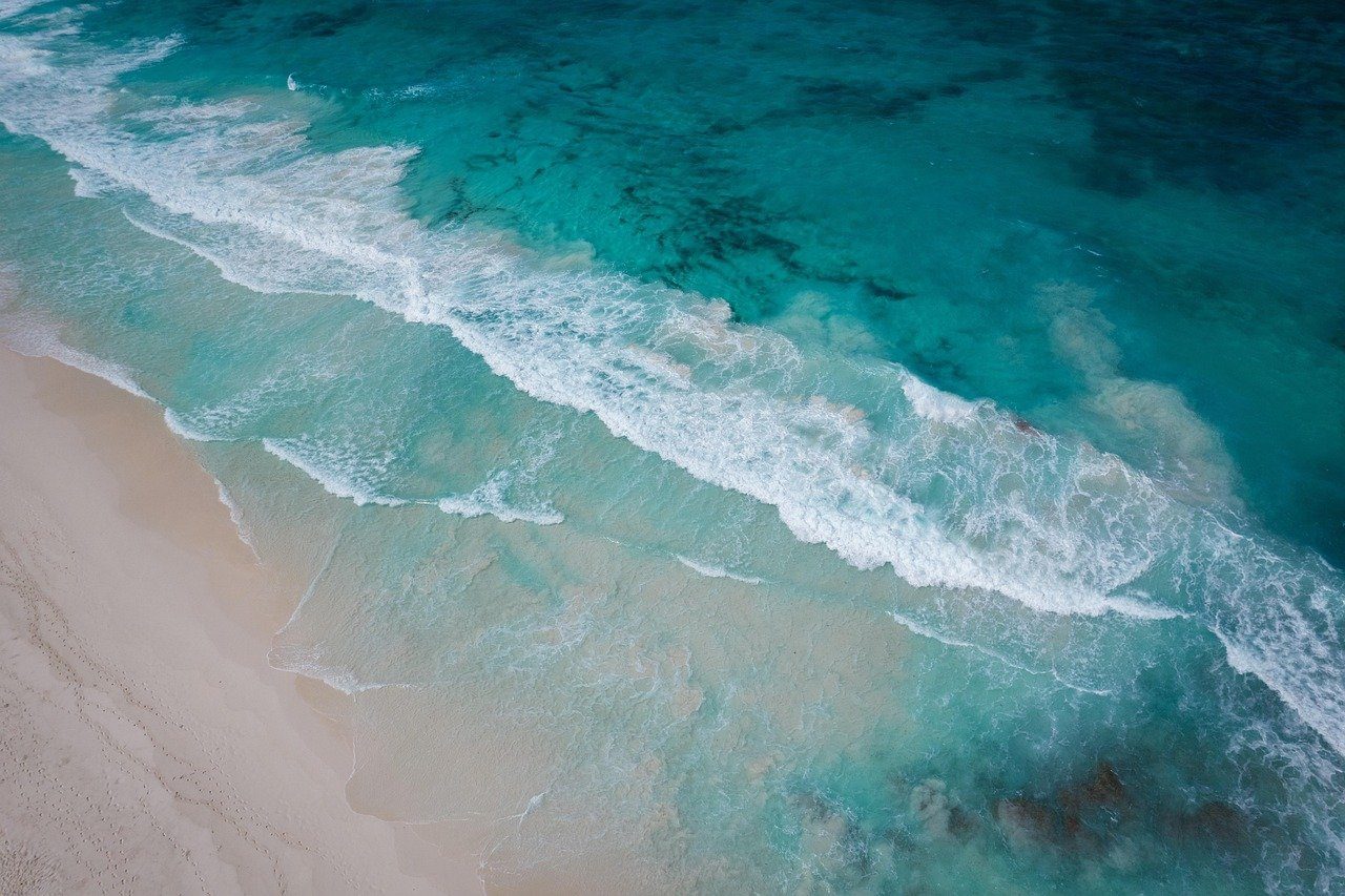 Aerial view of turquoise surf breaking on a sandy beach